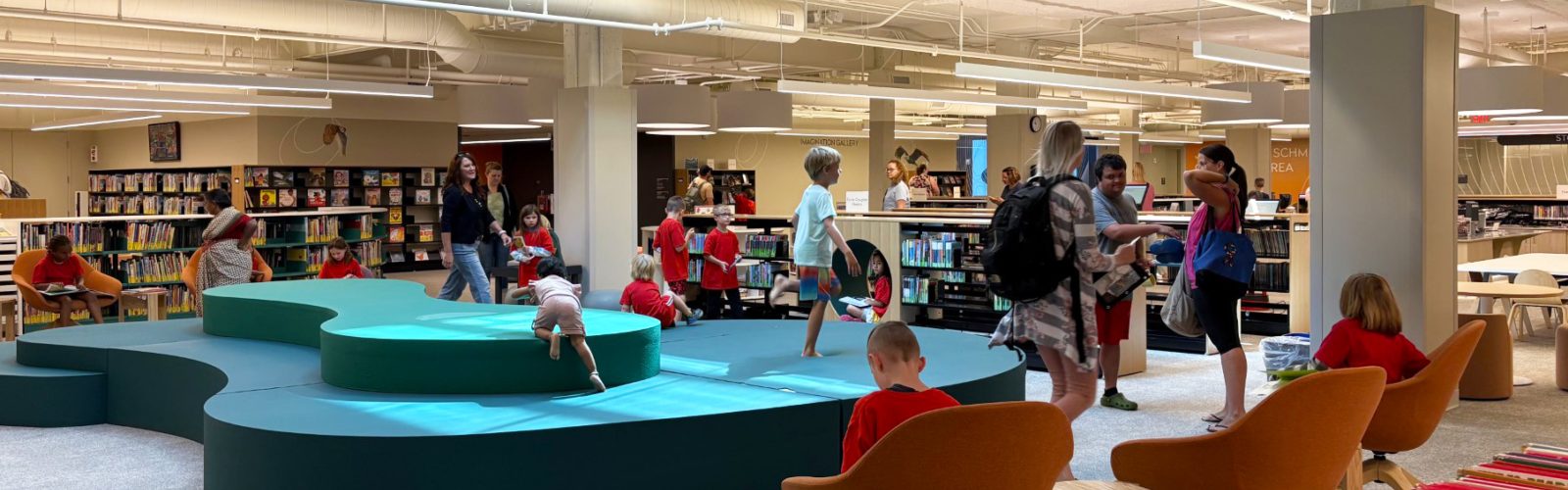 A library filled with children playing and people conversing.