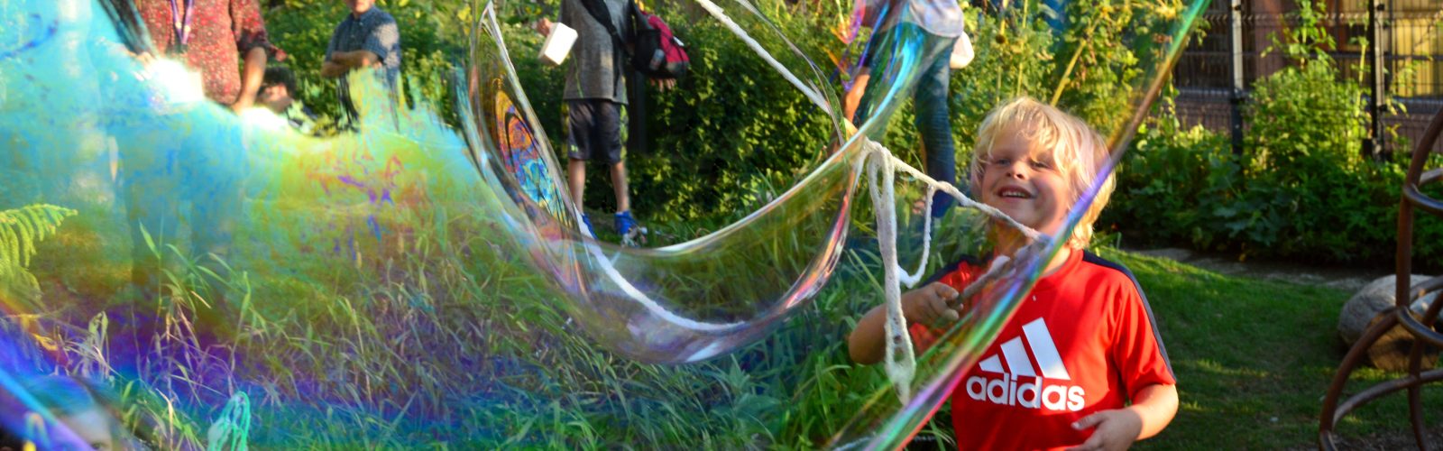 Child making a large colorful bubble.