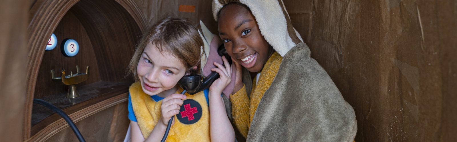 Two children listening to a play phone that gives positive affirmations.